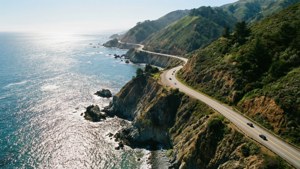 海岸公路，汽車沿著懸崖行駛，俯瞰閃閃發光的海洋。