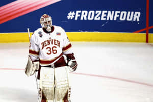 丹佛冰球守門員在 Frozen Four 錦標賽期間穿著栗色和白色裝備在冰場上。