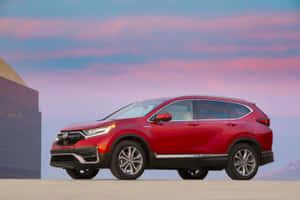 暮色中停泊在現代建築旁的紅色本田CR-V SUV。 — 本田 壁紙