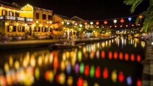 色彩繽紛的燈籠懸掛在運河上方，在夜間反射在燈光建築旁的水面上