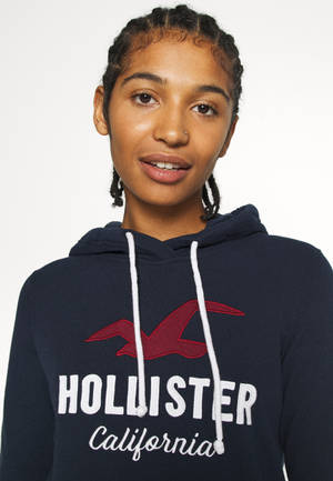 穿著帶有紅色標誌和白色抽繩的深藍色Hollister連帽衫的年輕女性。 — 蜂鳥 GIF 壁紙