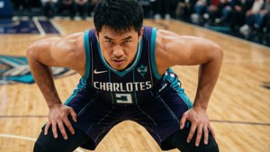 身穿夏洛特黃蜂隊球衣的籃球運動員在硬木球場上蹲下