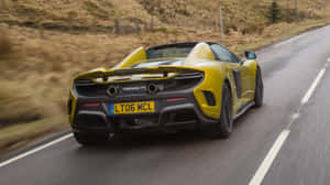 黃色McLaren跑車在日落時分的鄉村道路上疾馳。 — 2560x1440 壁紙