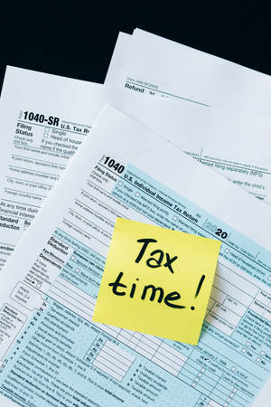 黃色便利貼寫有「Tax time!」，置於美國稅表上。