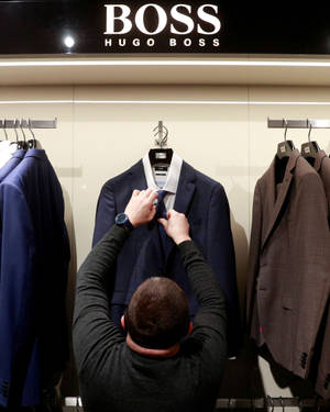 在零售店中調整 Hugo Boss 西裝人體模型領帶的人。