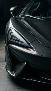 昏暗車庫中的黑色碳纖維McLaren跑車頭燈。