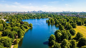 一個鬱鬱蔥蔥的綠色公園的鳥瞰圖，有藍色湖泊和遠處的城市天際線。