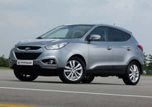 銀色Hyundai ix35 SUV停泊在瀝青路面上，後面有樹木。