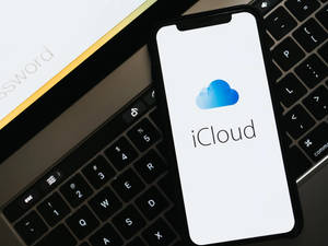 智能手機在鍵盤上顯示 iCloud 標誌，附近有密碼卡。 — 電腦 GIF 壁紙