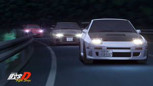 三輛動漫賽車在夜間於蜿蜒的山路上疾馳。