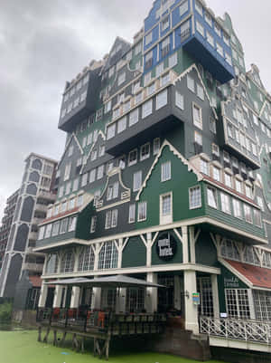 陰天時，一座現代階梯式山牆酒店建築矗立在綠色運河之上。 — 建築 壁紙