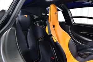 McLaren 跑車內部的黑色和橙色賽車座椅，帶碳纖維飾邊。 — MacBook Air M4 壁紙