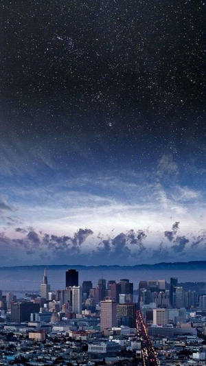 星空下的城市天際線，發光路燈和雲彩。 — iOS 13 GIF 壁紙