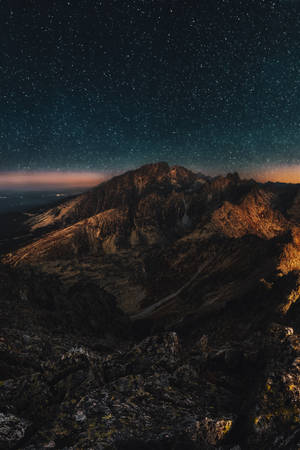 暮色中星光閃耀的山脈，山峰發光，天空黑暗。