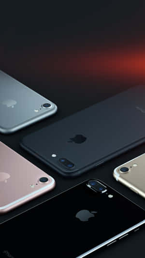五部不同顏色的Apple iPhone對角線排列在深色表面上，帶有紅色燈光。
