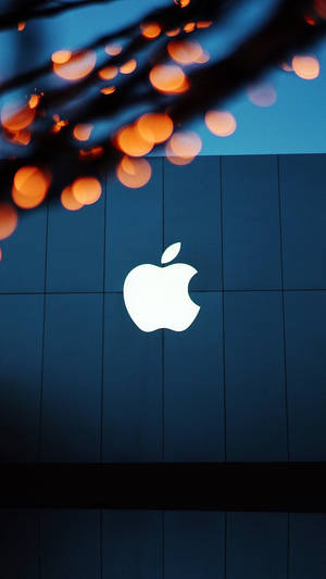 Apple標誌在藍色瓷磚牆上發光，背景有橙色燈光。 — 光 壁紙