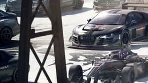 白天維修站車庫內的黑色奧迪 R8 和一級方程式賽車。