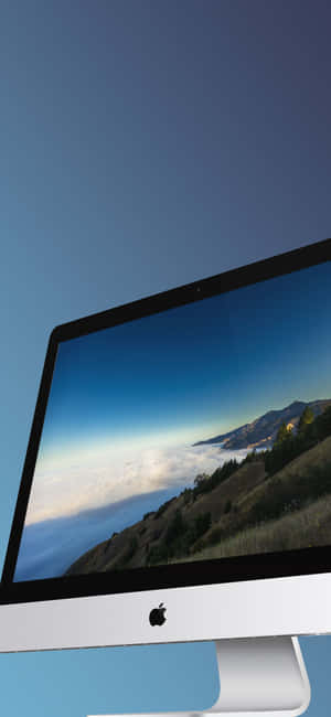 銀色 iMac 顯示日落時雲層上方的山景。