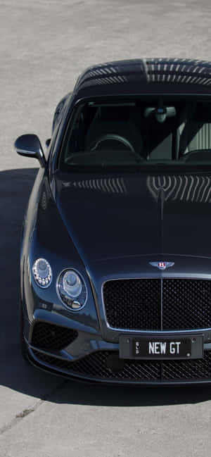 黑色Bentley New GT跑車在明亮陽光下停泊在混凝土上。 — iPhone 14 Pro Max 壁紙