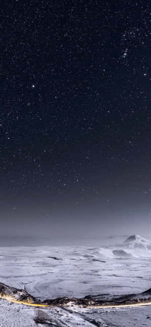 星空夜空下的積雪山脈，下方有一條發光的道路。 — 冬天 壁紙