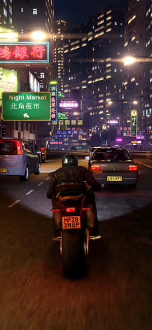 夜晚街道上的電單車手，背景有霓虹招牌和建築物。 — Pixel 8a 壁紙