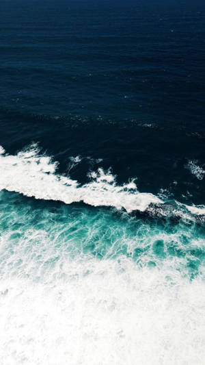 海浪在綠松石色水中破碎並帶有白色泡沫的航拍視圖。