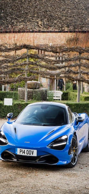 藍色McLaren 720S停泊在葡萄園環境中，有涼棚和石牆。 — iPhone 14 Pro Max 壁紙