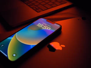 手提電腦上的智能手機，彩色屏幕和溫暖光線 — 美學 iPhone 壁紙