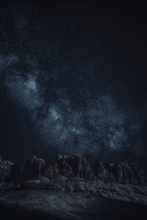 在繁星點點的夜空下，黑暗崎嶇的山脈，銀河清晰可見。