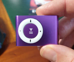 手拿著紫色 iPod shuffle 音樂播放器。 — 音樂 GIF 壁紙