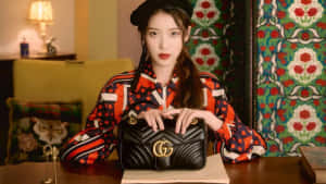 身穿圖案襯衫的女性在室內拿著黑色Gucci手提包。