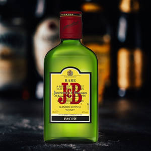 一瓶綠色 J D & J & B Rare Blended Scotch Whisky 放在深色酒吧檯面上，背景燈光模糊。