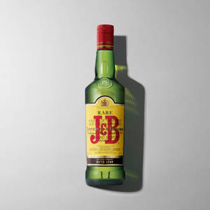 灰色背景上帶有紅色蓋子的綠色J&B Rare威士忌瓶。