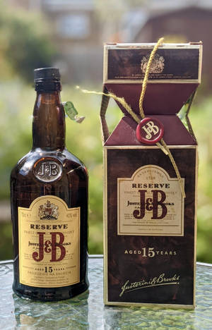 一瓶J&B Reserve 15年威士忌和盒子放在戶外的玻璃桌上。