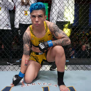 藍色頭髮的女性MMA拳手跪在UFC八角籠內。