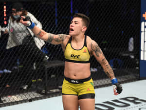 女性MMA拳手身穿黃色裝備在UFC八角籠內慶祝勝利。