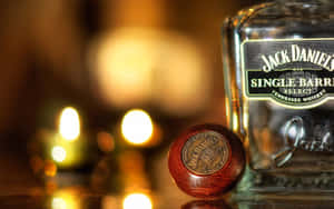 Jack Daniel's 威士忌酒瓶和瓶塞，背景有柔和焦點的發光蠟燭。 — 16:10 壁紙