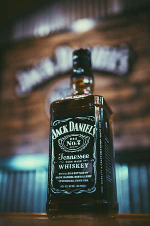 酒吧上的 Jack Daniel's 威士忌酒瓶，背後有模糊的釀酒廠標誌。 — 2:3 壁紙