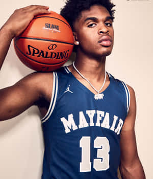 身穿藍色 Mayfair 球衣的年輕籃球運動員伸出舌頭拿著 Spalding 球。