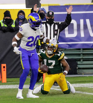 NFL美式足球員跪地持球，對手在雪地球場逼近。