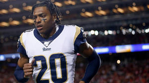 身穿公羊隊球衣的美式足球員在夜間比賽中奔跑。 — NFL 美式足球 GIF 壁紙