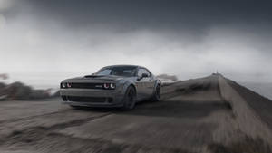 灰色嘅 Dodge Challenger Hellcat 喺有霧嘅天氣下，喺海岸公路上高速行駛。
