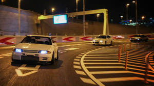 白色賽車在夜間賽道上疾馳，車頭燈發光。