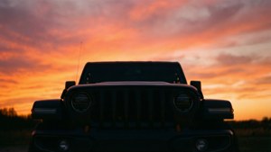 日落時分 Jeep Wrangler 的剪影，天空呈現鮮豔的橙色和粉紅色