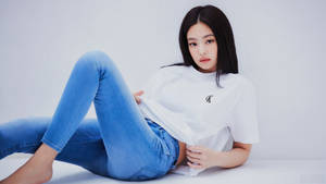 年輕女士身穿藍色牛仔褲和白色T恤在白色地板上躺著。