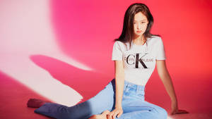 一位穿著Calvin Klein牛仔褲和T恤的女性在粉紅色攝影棚中擺姿勢。