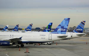 JetBlue飛機停泊在機場停機坪，背景為城市天際線。