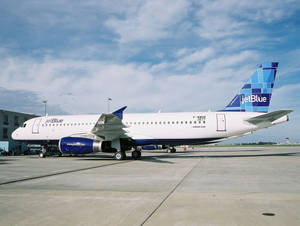 JetBlue 飛機停泊在機場停機坪上，藍天白雲