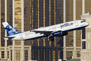 日落時分，JetBlue飛機在高樓大廈之間降落。