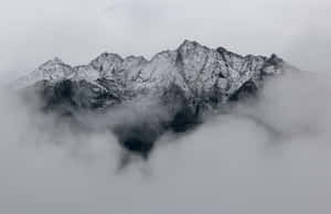 在陰天，積雪的山峰從濃密的雲層中浮現。